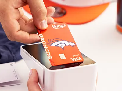 Hand making a payment with a Denver Broncos debit card 