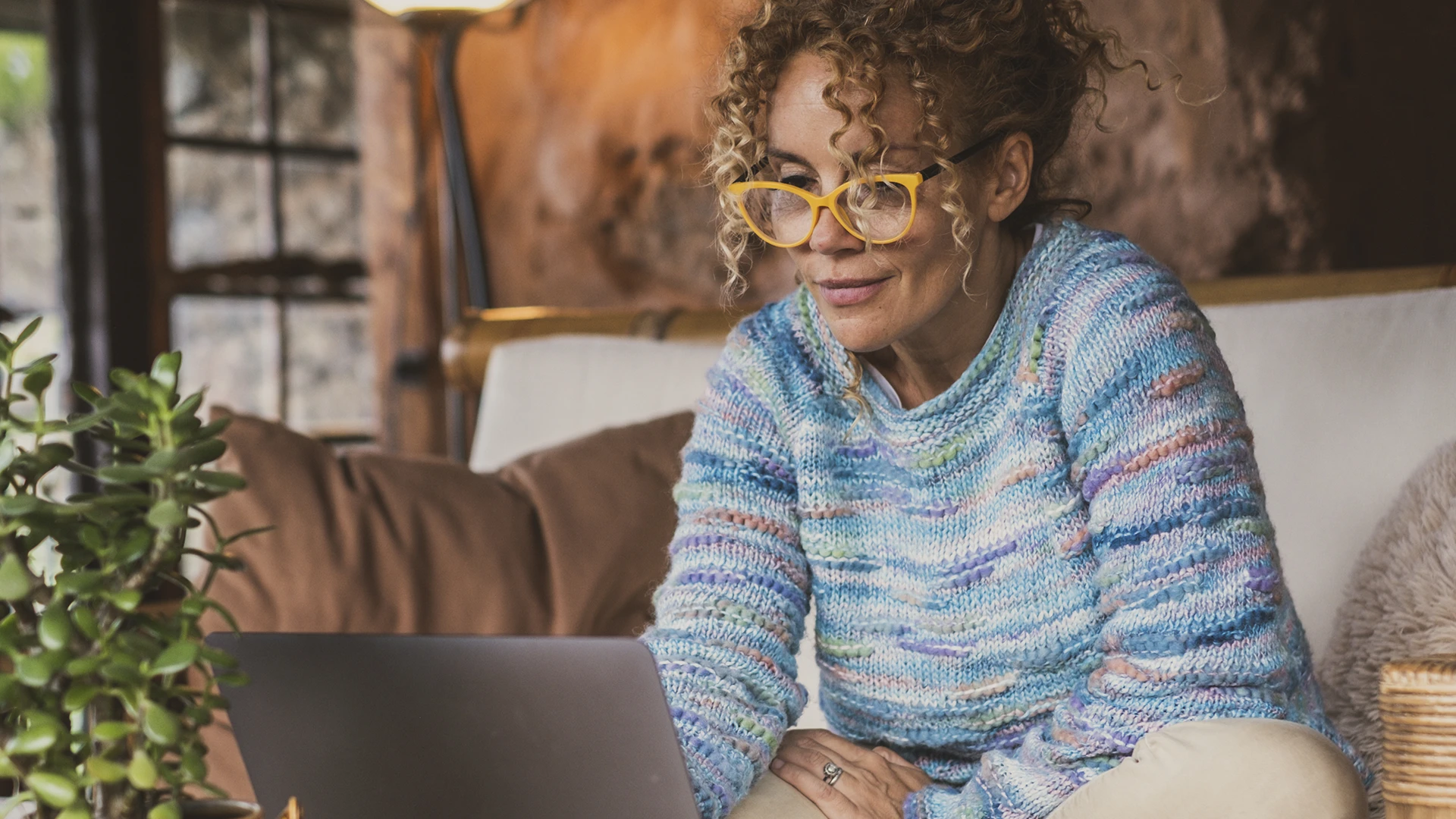 An older woman sitting on her couch using her laptop