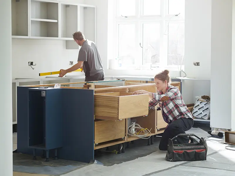 A couple working together to fit kitchen cupboards