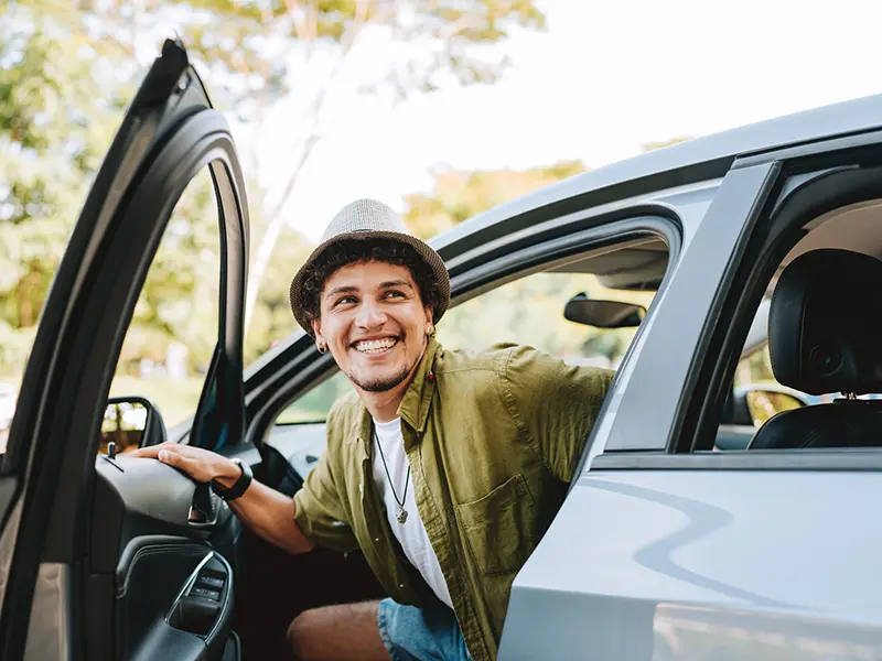 Young man getting out of a car on a road trip
