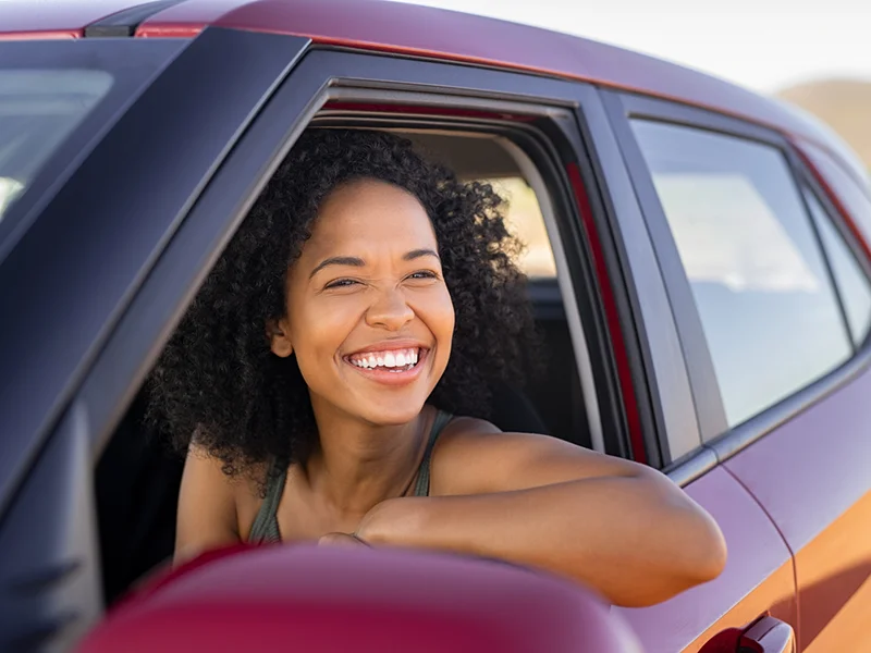 Woman driving a car and smiling out the window