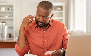 Woman sitting at table depositing her check with her phone.