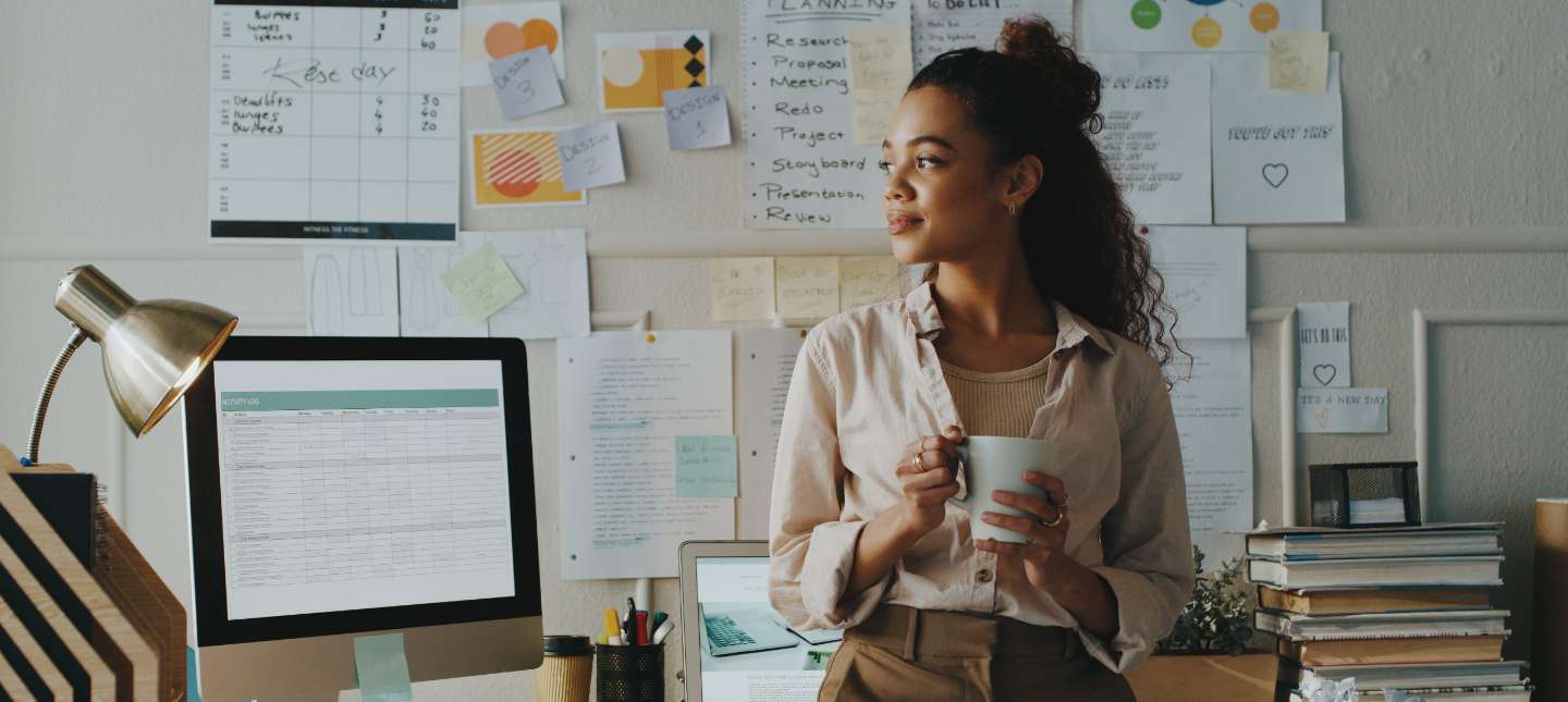 young woman standing at her desk holding a mug