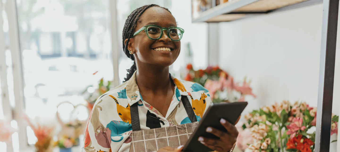 Middle age woman, smiling and staring at her small business holding a phone
