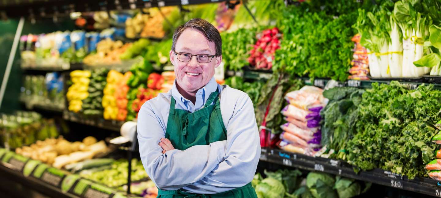 Young man working at a grocery store and smiling