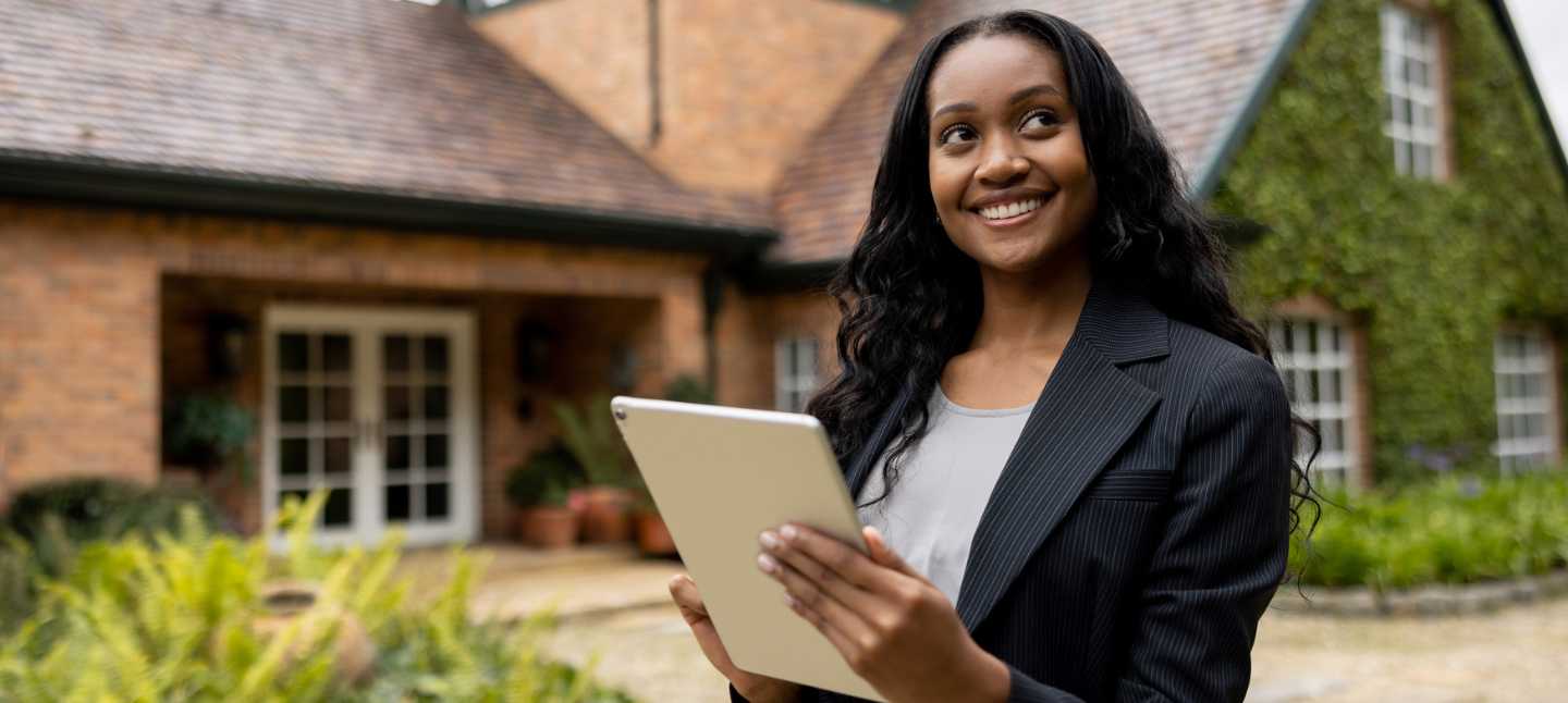 Woman holding clipboard standing in front of a house.
