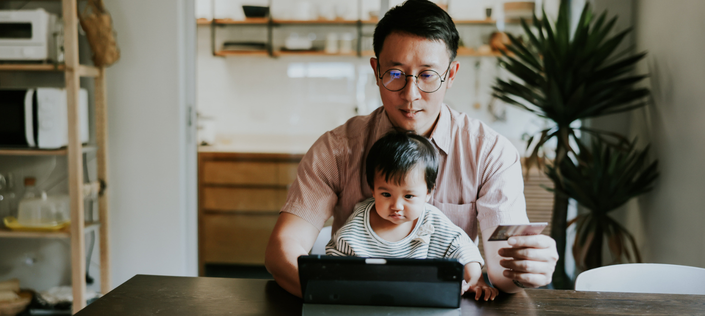 Man sitting with his baby at a laptop.