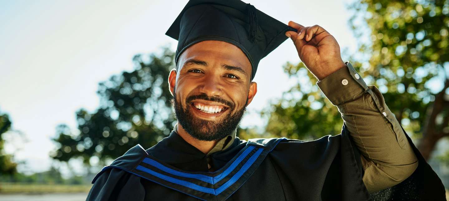Man smiling dressed with a graduation gown