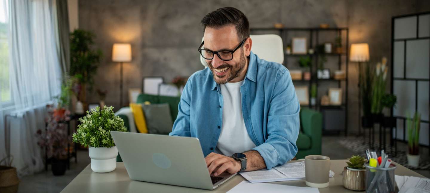 Smiling young man using laptop while working from home office