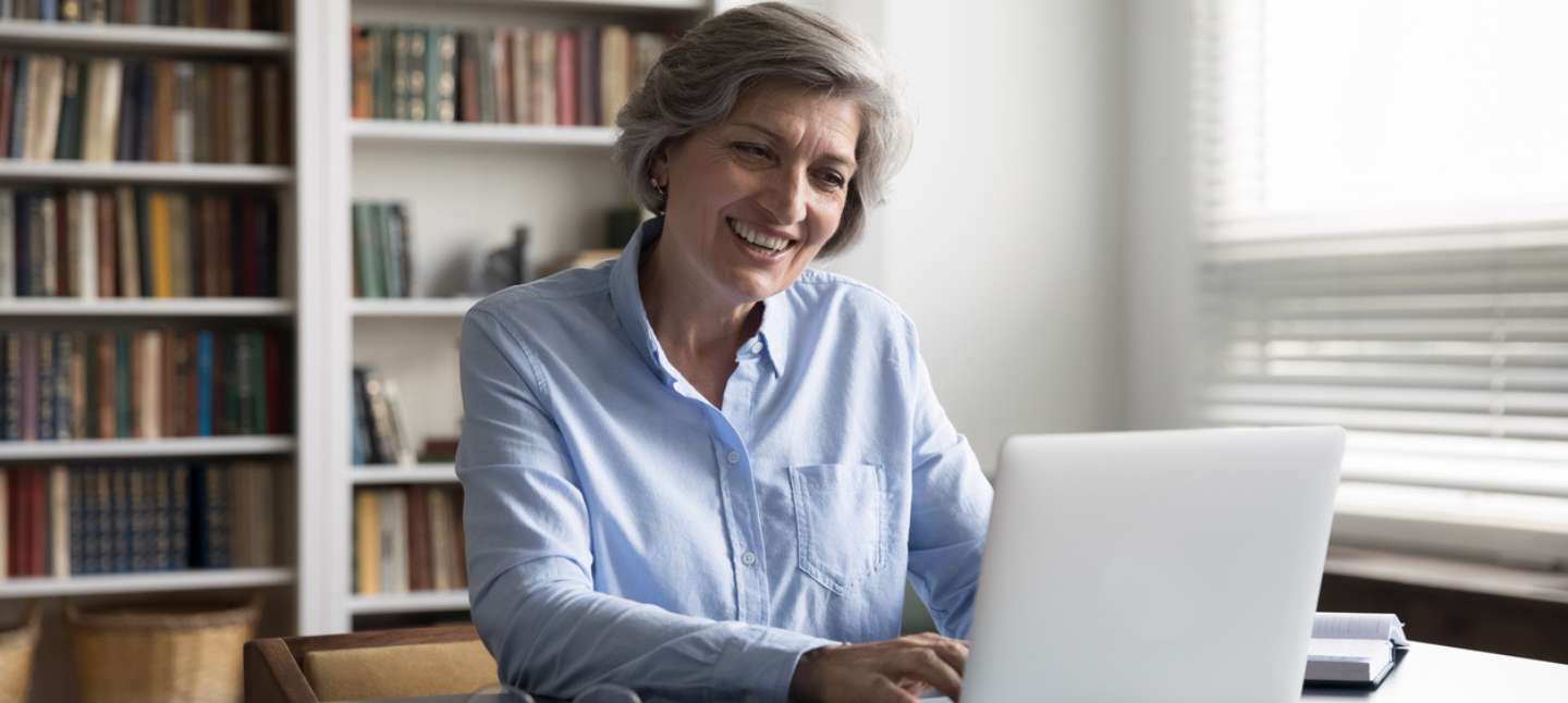 An older woman typing on her laptop