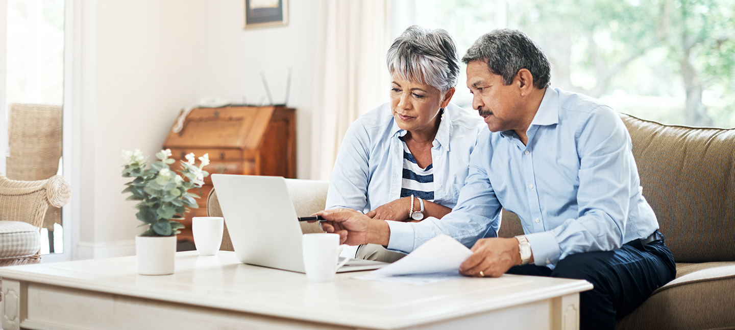 older couple sitting on couch looking at a laptop