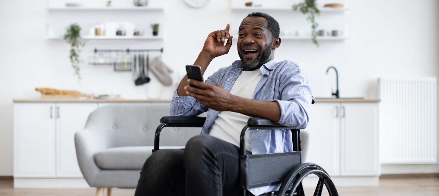 Middle age men in a wheelchair, holding the phone and smiling