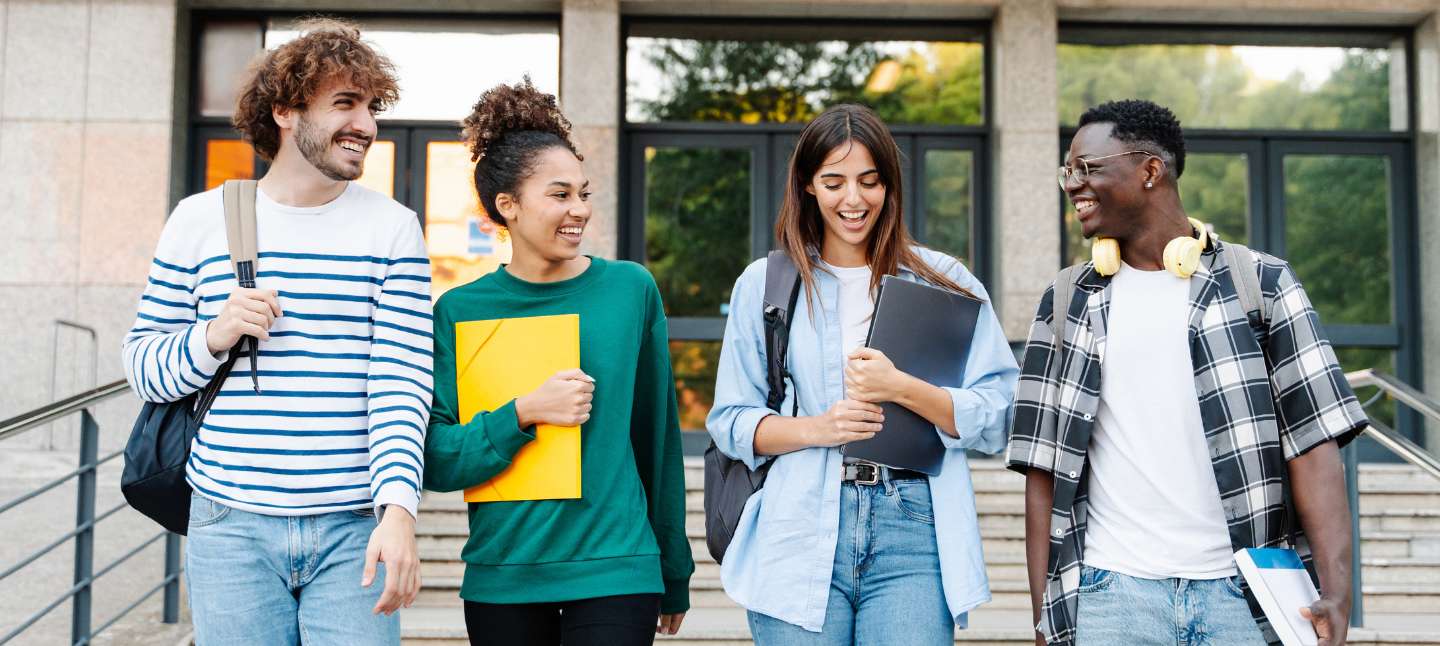 Four college students laughing and walking