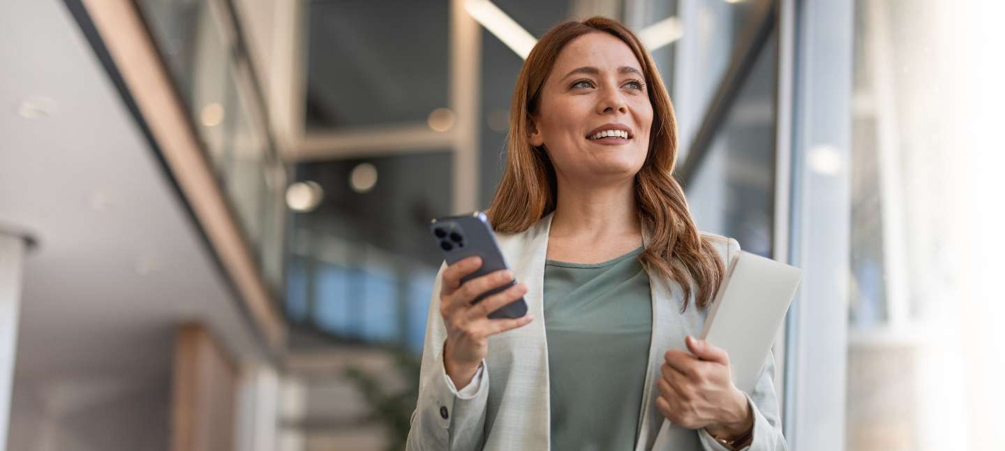 Caucasian young woman smiling and holding her phone