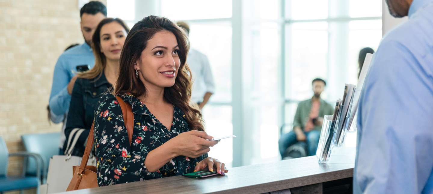 Adult woman smiles as she listens to the member service representative talk to her about products and services they have at the credit union.