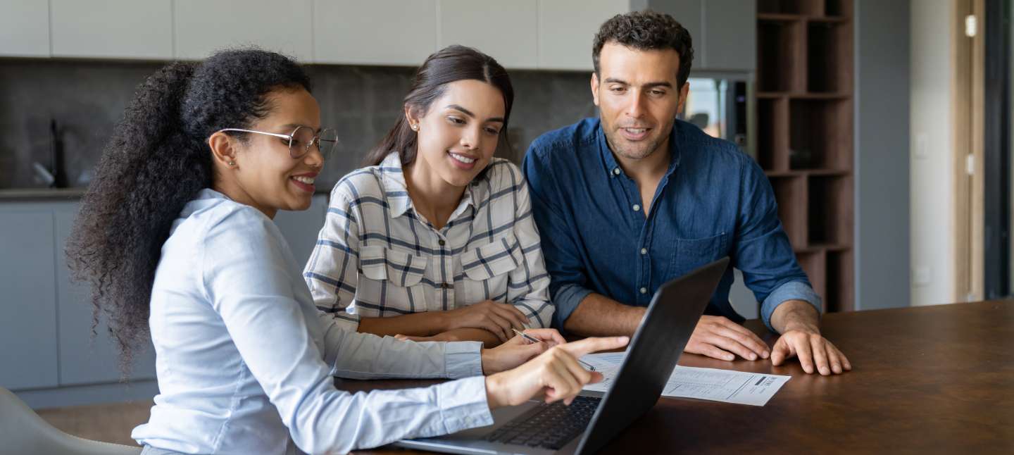 Happy Latin American couple talking to a financial advisor about buying a house.