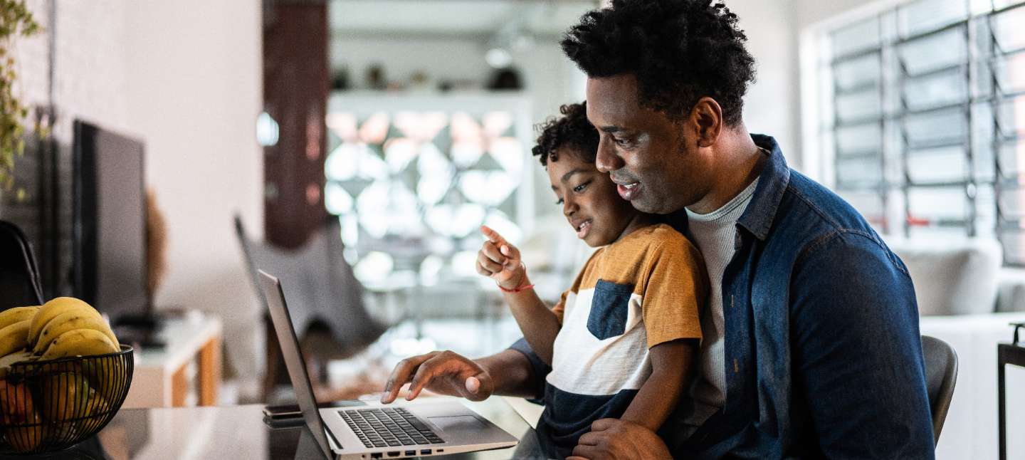 father and son looking and typing on a laptop