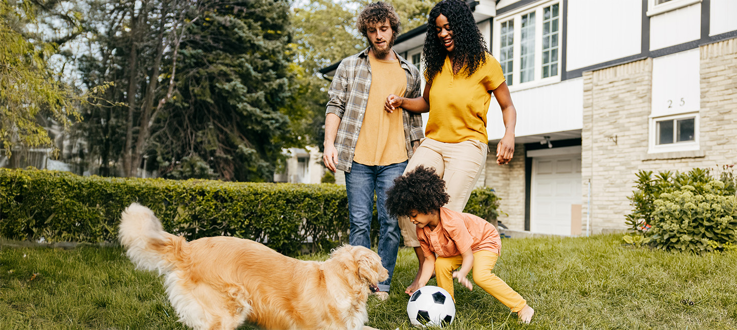 Family playing soccer in their yard with their dog