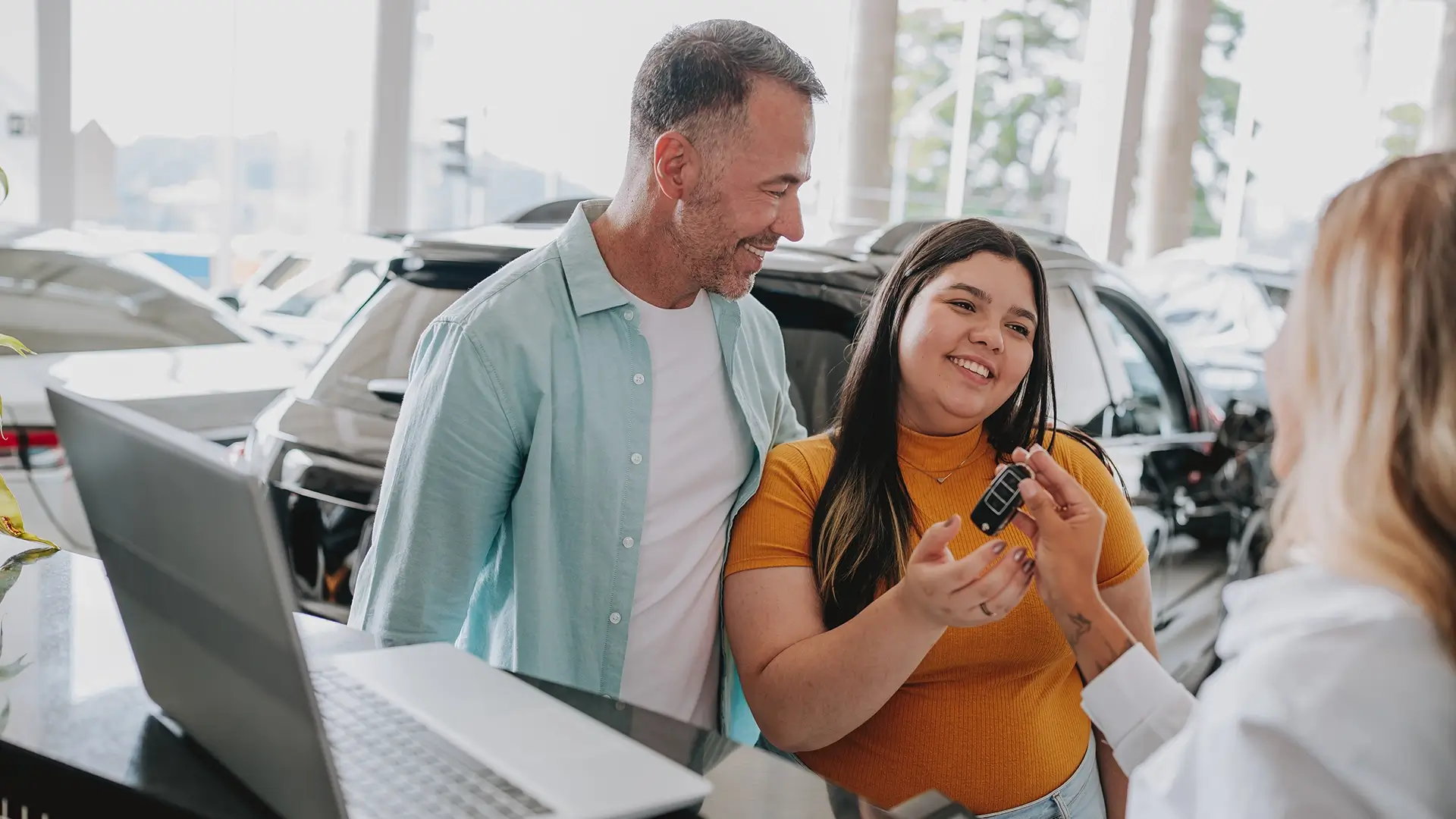 A young woman receiving keys to her car