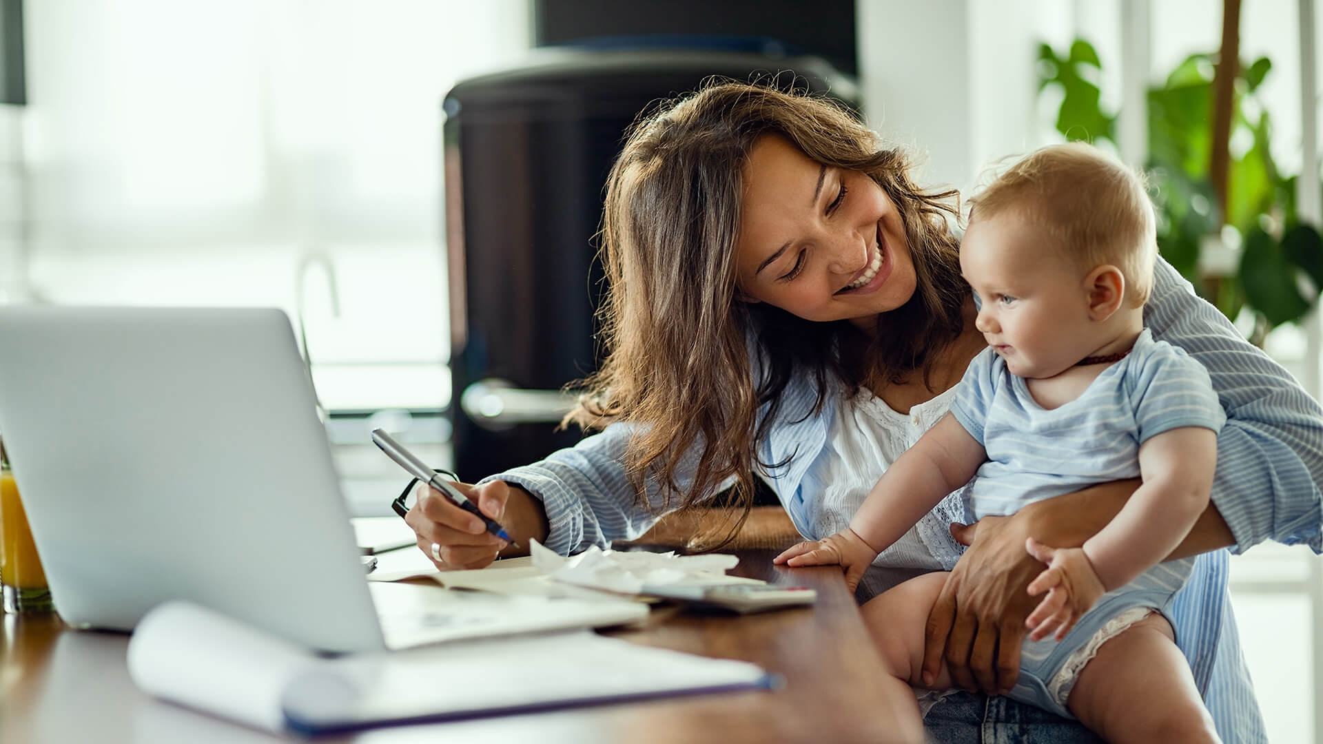 Happy mother talking to her baby while working