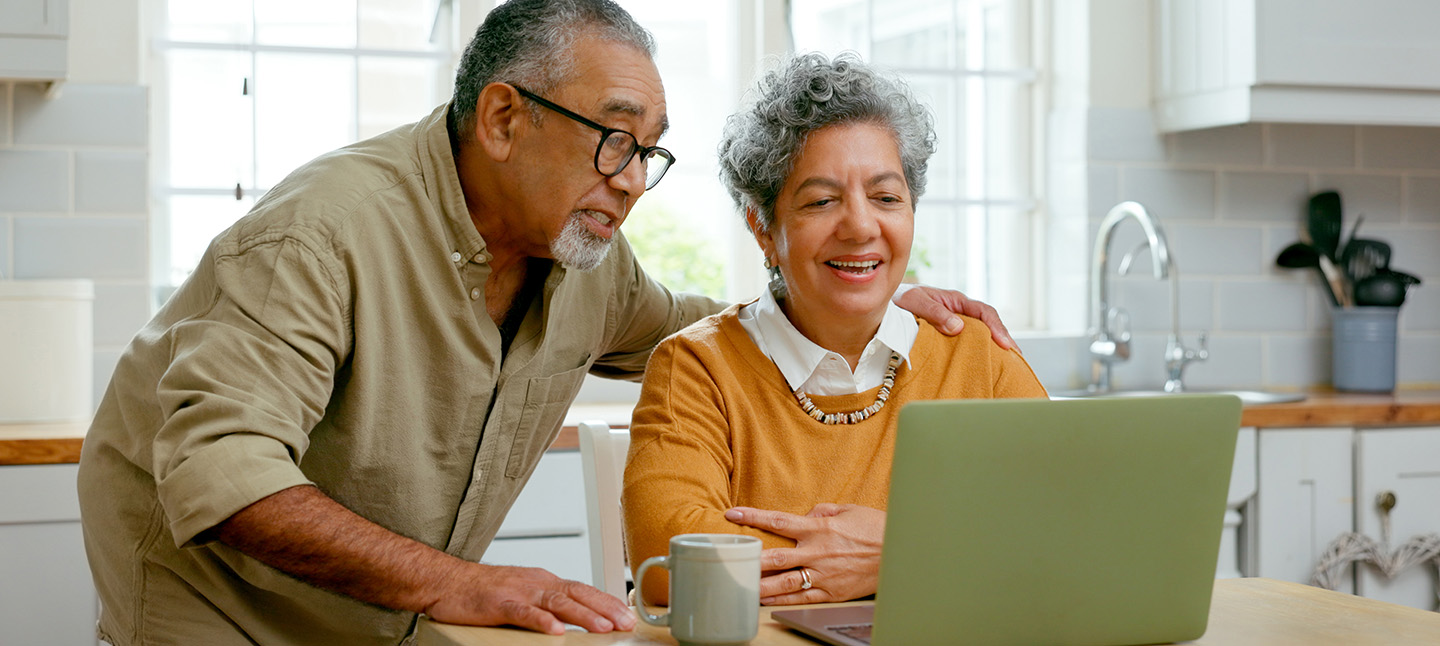 A senior couple in their kitchen browsing website at home