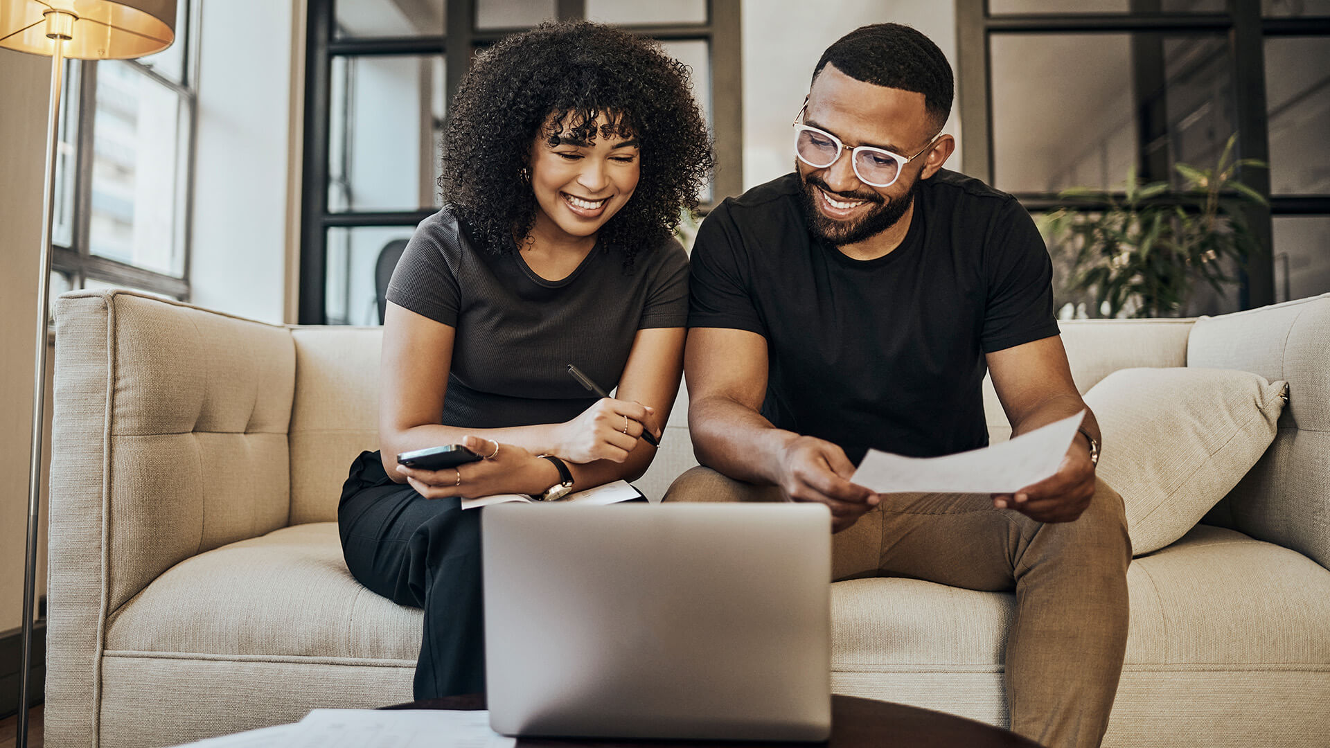 Young couple looking at paperwork and working on their laptop