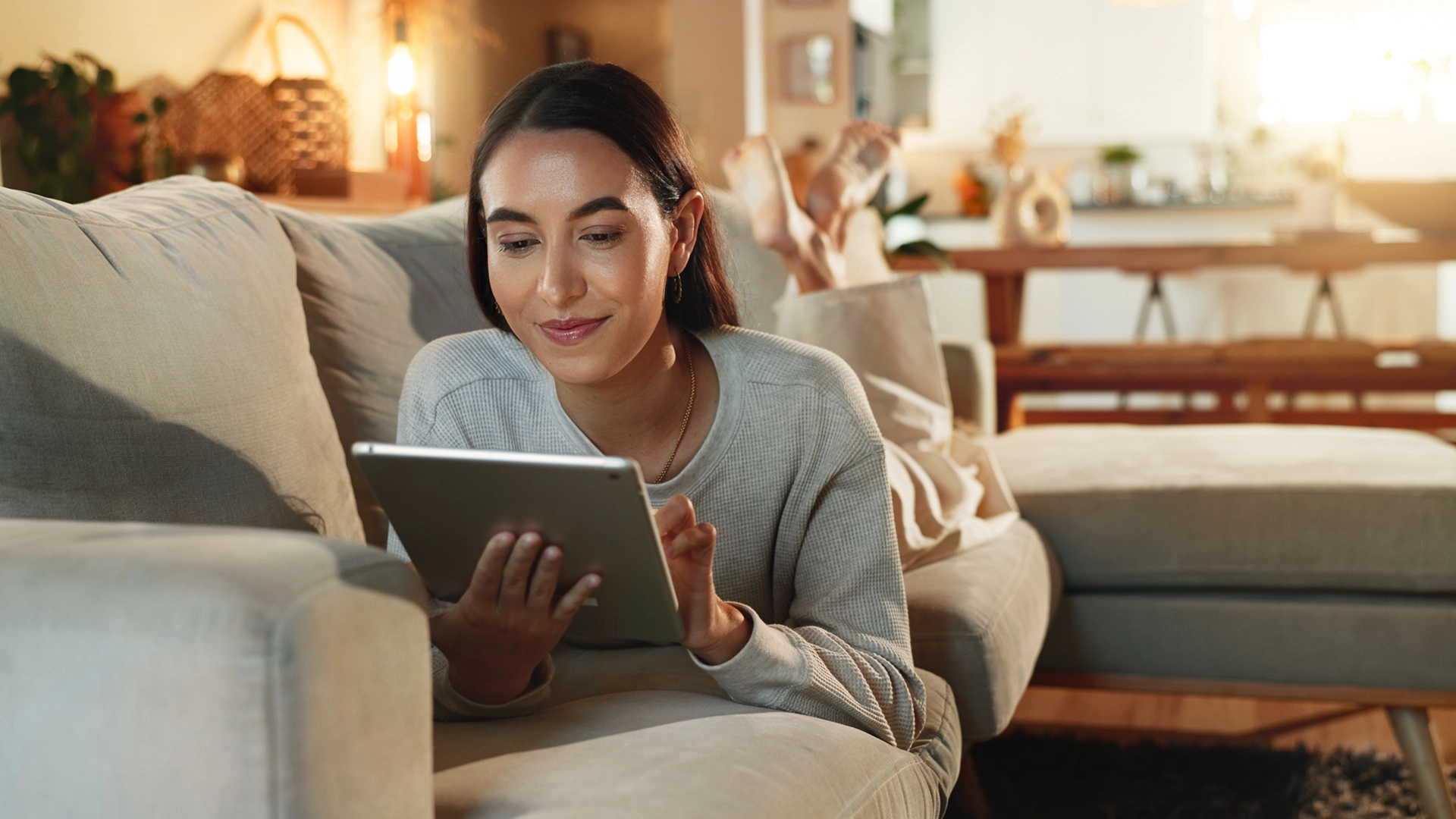  A woman on her sofa in the living room using her tablet