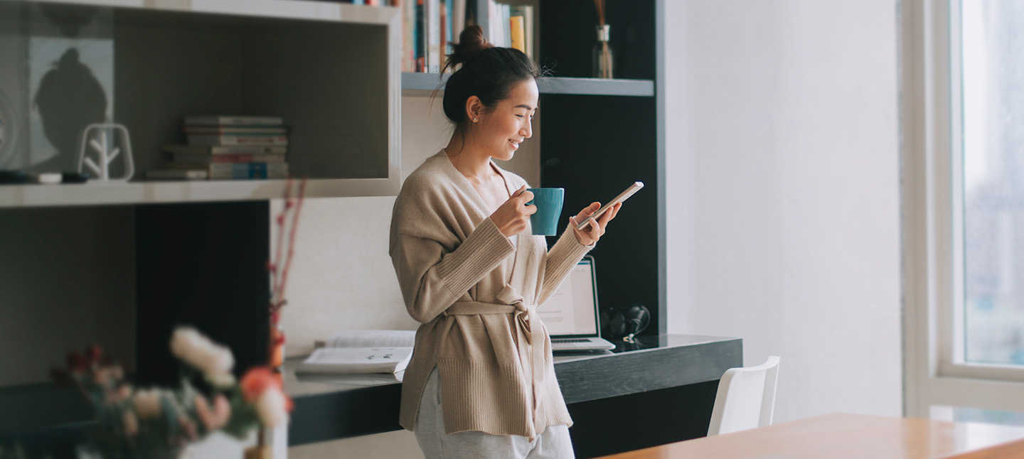 An Asian Chinese woman enjoying her afternoon tea while scrolling on her phone