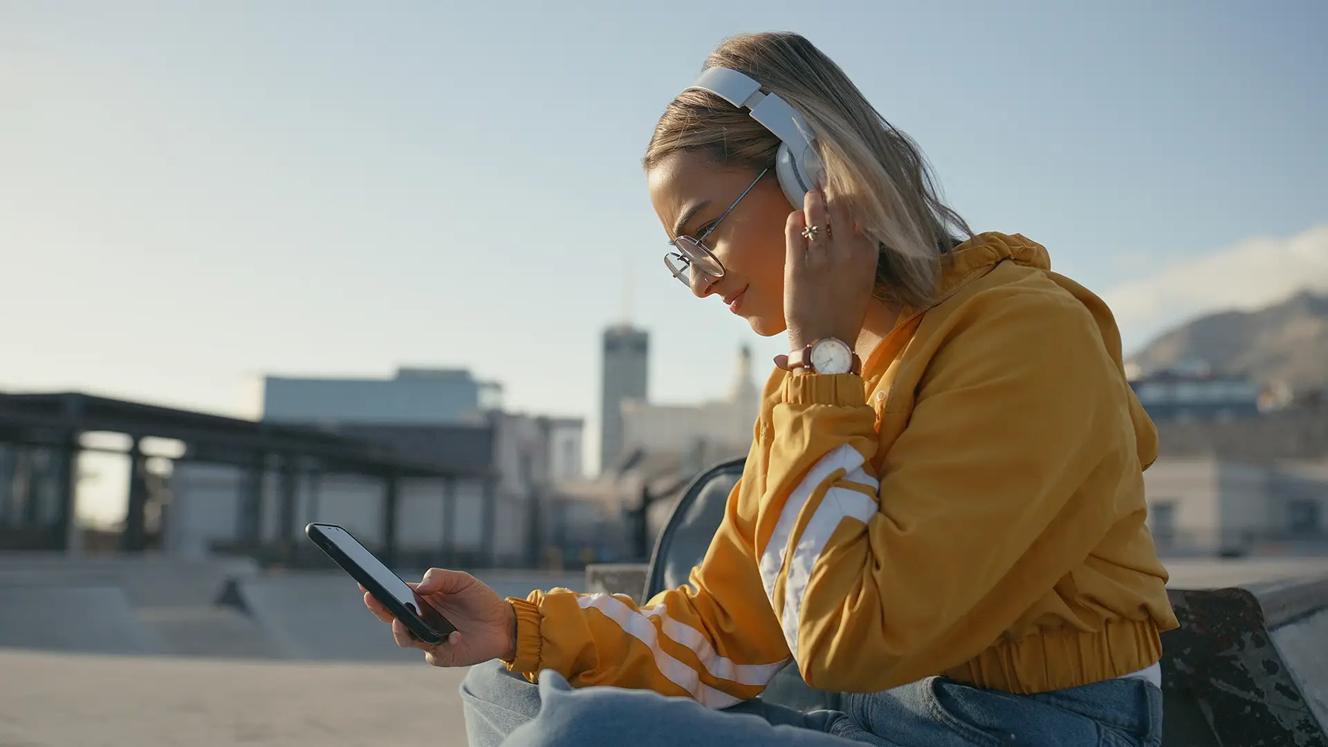 A young woman sitting outside organizing her apps on her phone