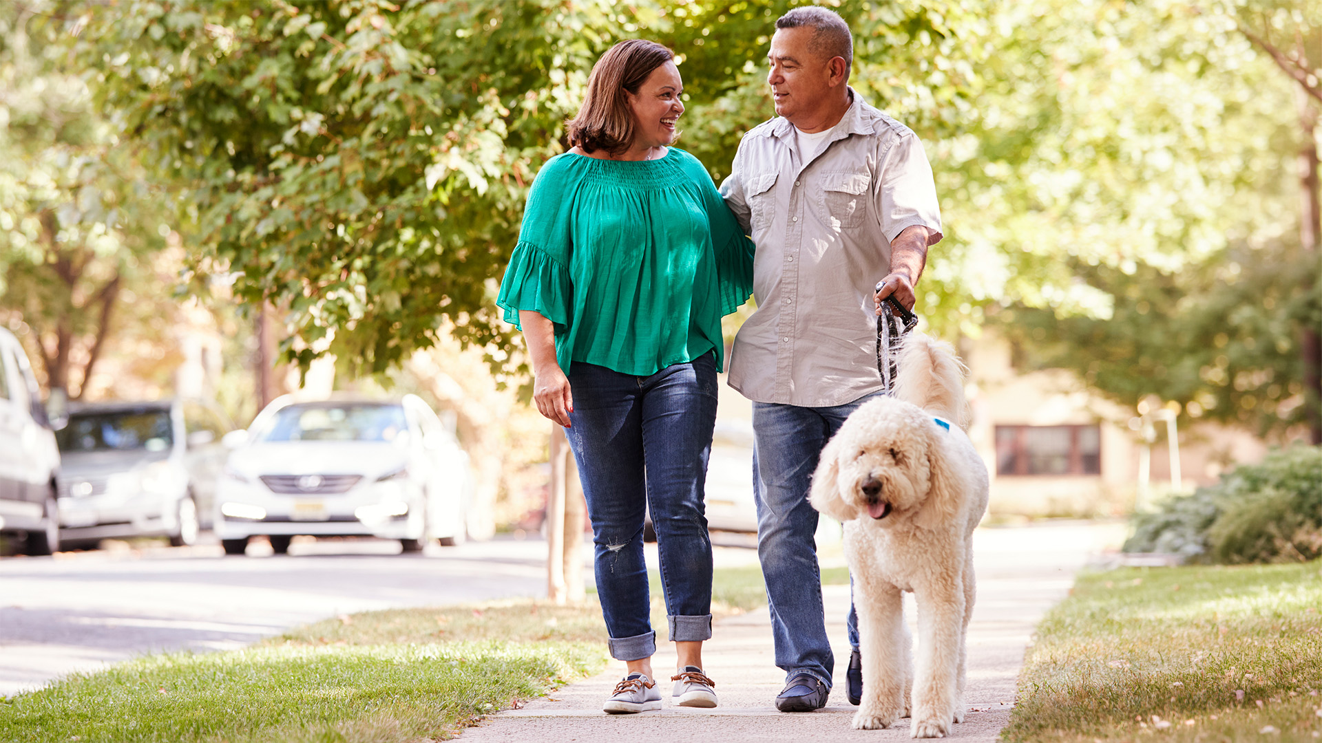 A senior couple walking their dog in a suburban neighborhood