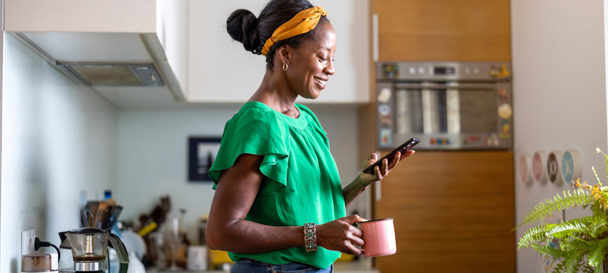 Mature women using smartphone in the kitchen at home
