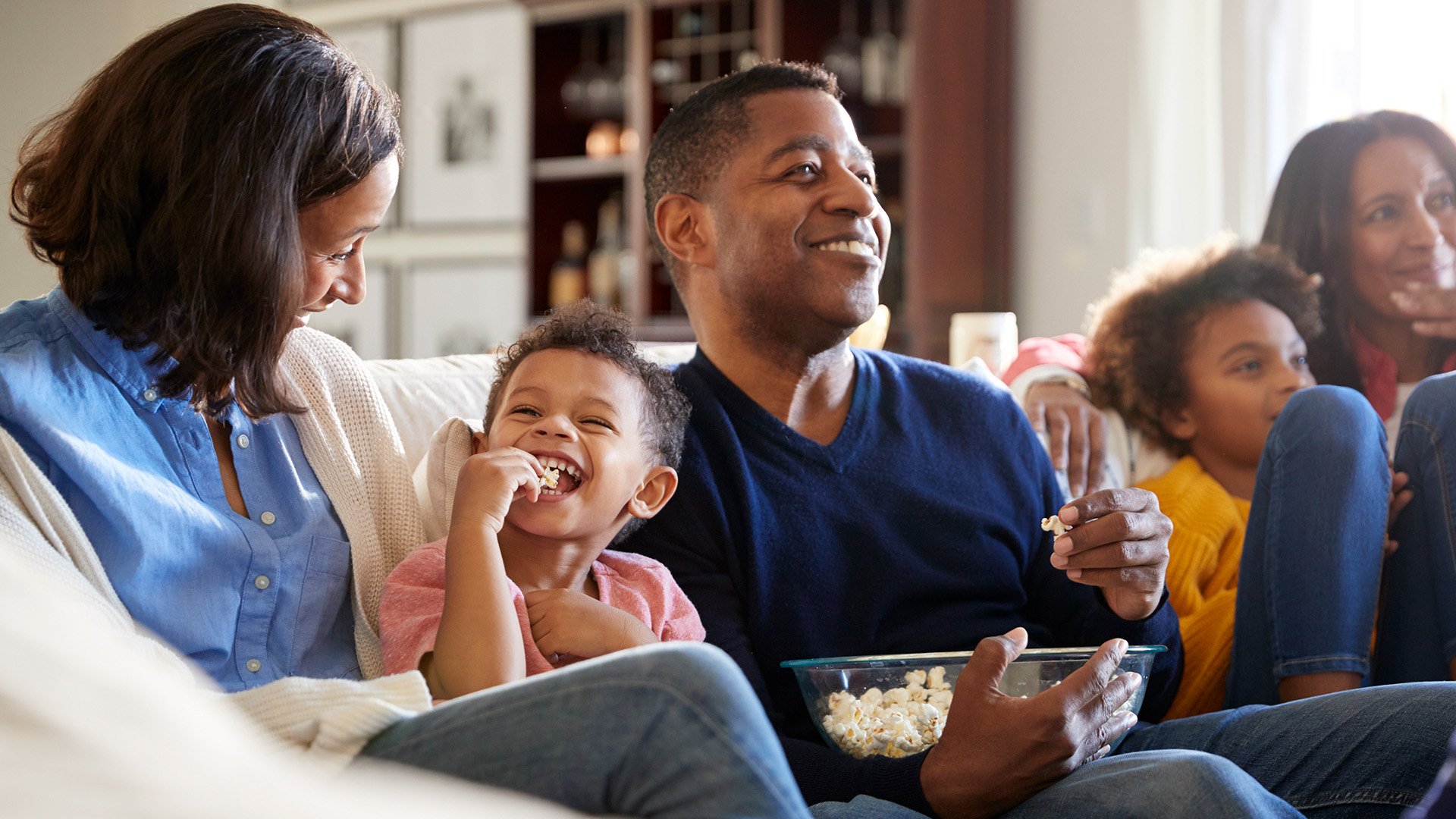 A family sitting on the couch watching TV
