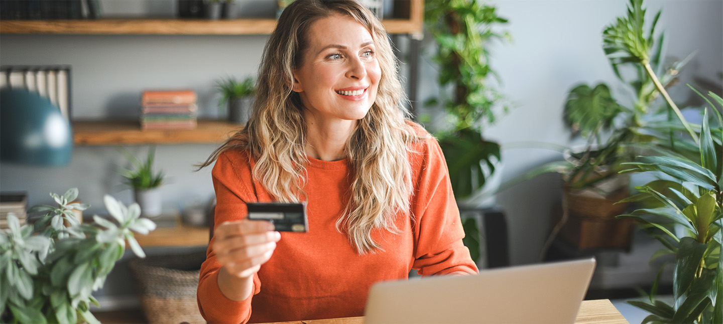 An adult woman daydreaming while holding her credit card