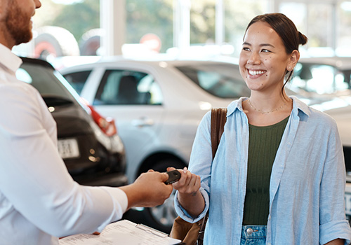 Saleman handing car keys to a woman 
